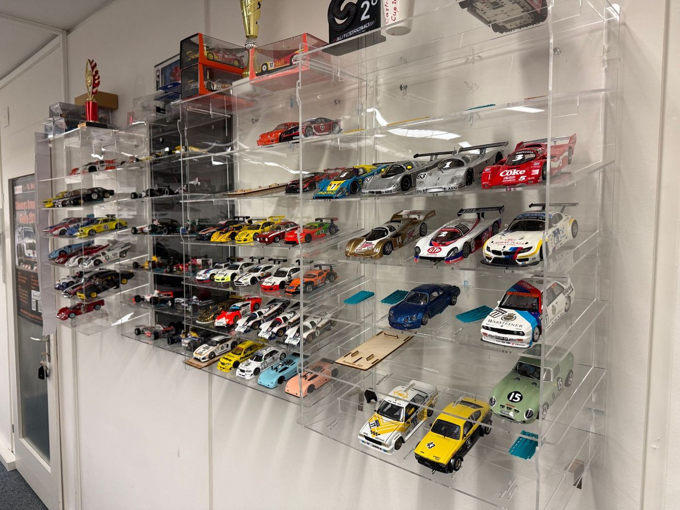 Wandvitrine aus Acryl mit Slotcars, Pokalen und Modellen in Originalverpackung